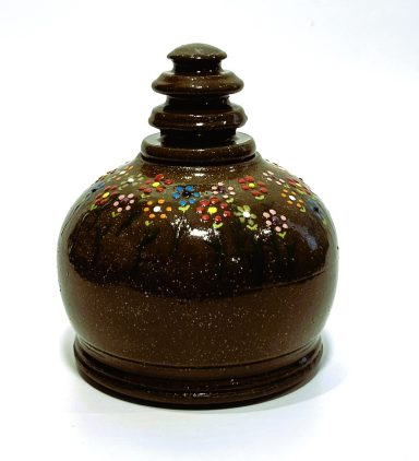 Dark brown clay body lidded vessel. Hand cut lid off the hump. Hand painted floral detailing. Yellow glazed interior. H-4.5in x W-4in.