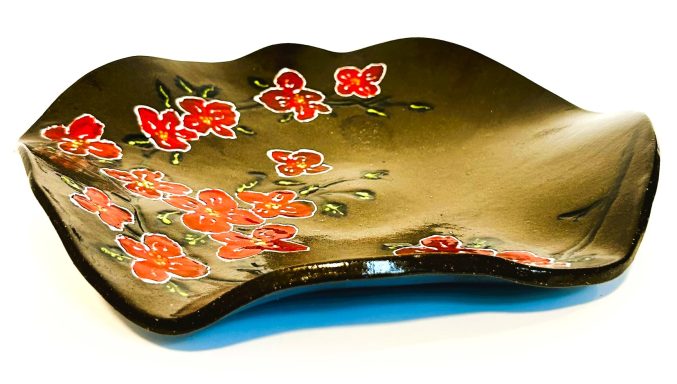Dark brown clay base. Wavy surface. Hand painted flower detail. Clear glaze cover. Diameter-11in.