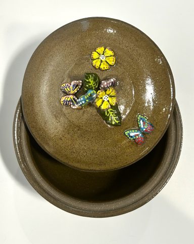 Dark clay base. Lidded Pot. Hand painted porcelain butterfly garden themed appliques. Clear glaze interior. H-6 1/8in x Diameter-7 3/8in.